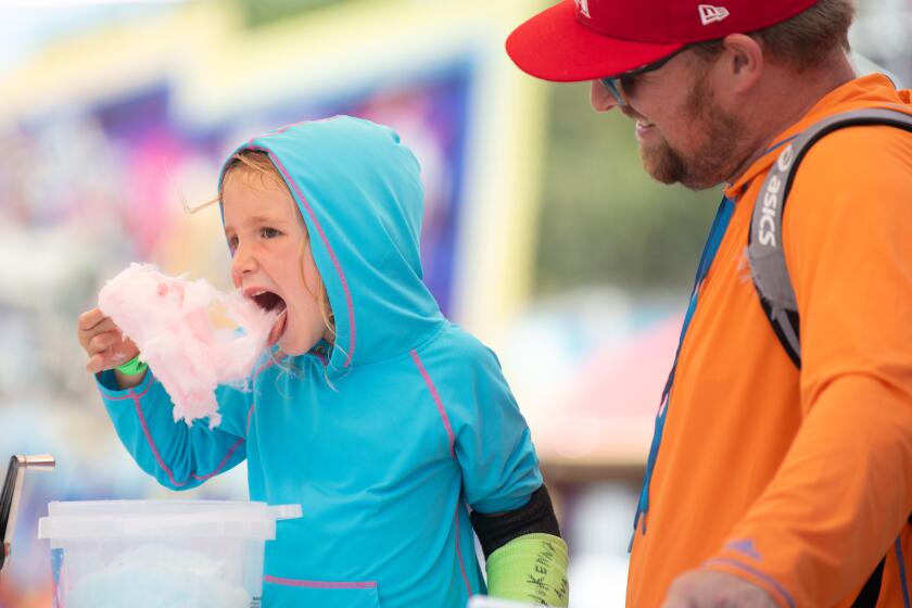 Jeff Haluck watches his son Finley indulge in cotton candy during opening day at the OC Fair Friday, July 19.
