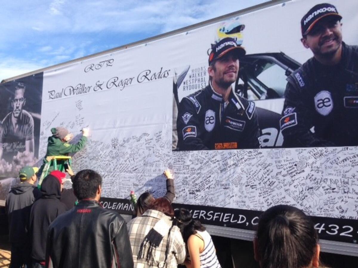 Fans of actor Paul Walker sign a memorial placard.