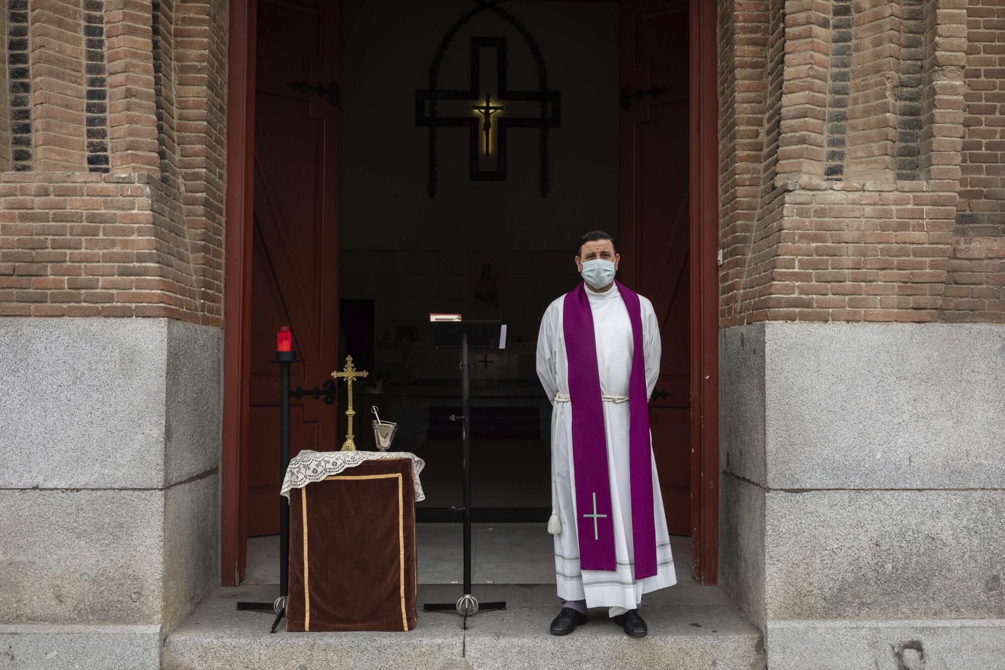 SPAIN: A priest wearing a face mask waits in front the cemetery chapel  in Madrid. 
