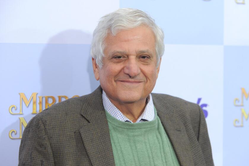 Michael Lerner smiles in a brown suit and green sweater