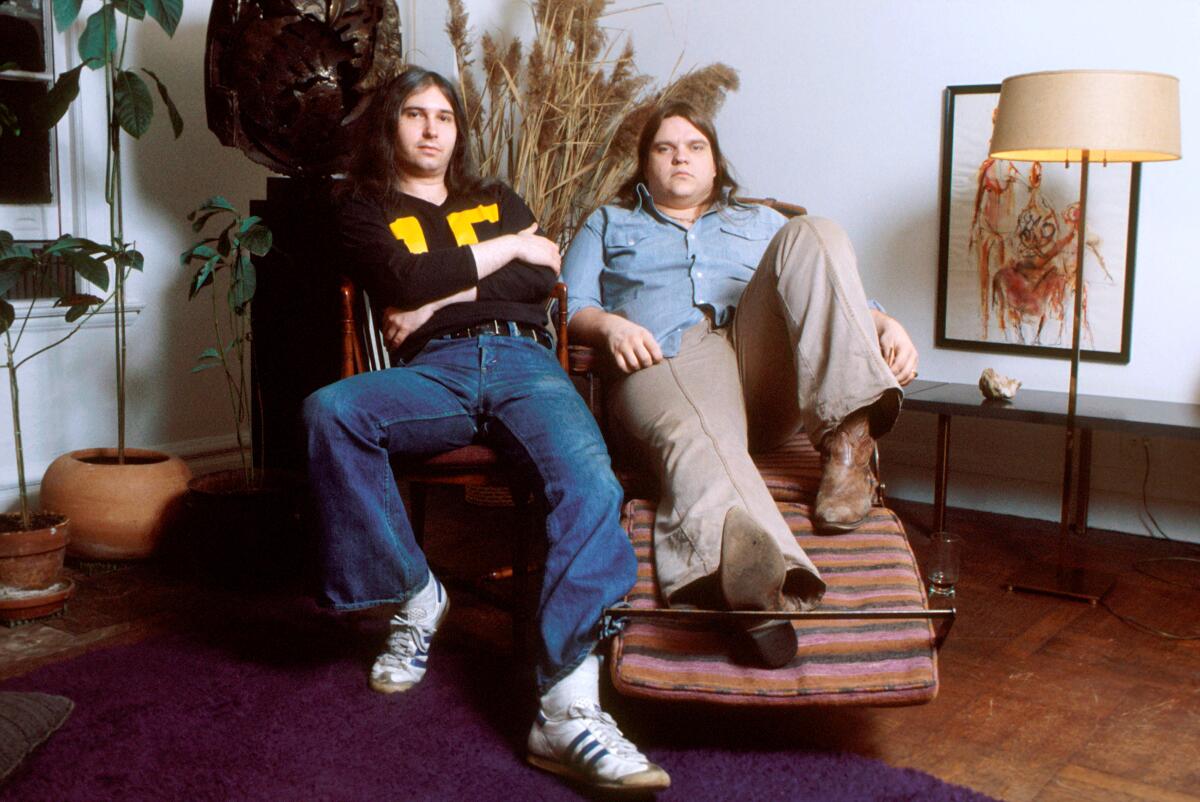 Jim Steinman and Meat Loaf pose for a photo seated.