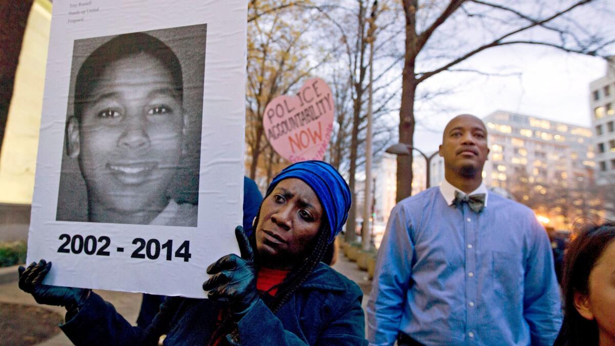 Tomiko Shine, left, holds a photo of Tamir Rice, a boy fatally shot by a Cleveland police officer, in Ferguson, Mo. on Dec. 1, 2014.