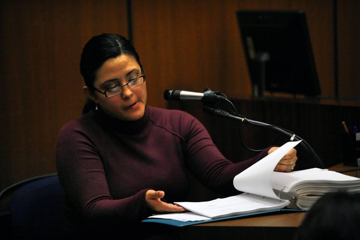 Bell City Clerk Rebecca Valdez leafs through paperwork for a specific exhibit at the 2011 preliminary hearing for two former Bell officials accused of corruption. Testifying Wednesday at the trial of six former council members, she said the signatures on many city documents were forged.