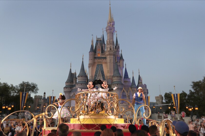 FILE - Mickey and Minnie Mouse perform during a parade as they pass by the Cinderella Castle at the Magic Kingdom theme park at Walt Disney World in Lake Buena Vista, Fla. The theme park resort announced Tuesday, Feb. 15, 2022, that face coverings will be optional for fully-vaccinated visitors in all indoor and outdoor locations, with one exception. Face masks still will be needed for visitors ages 2 and older on enclosed transportation, such as the resort's monorail, buses and the resort's sky gondola. (AP Photo/John Raoux, File)