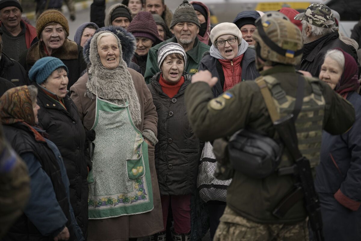 Civilians cheer along with a Ukrainian serviceman as a convoy of military and aid vehicles arrives in the formerly Russian-occupied Kyiv suburb of Bucha, Ukraine, Saturday, April 2, 2022. As Russian forces pull back from Ukraine's capital region, retreating troops are creating a "catastrophic" situation for civilians by leaving mines around homes, abandoned equipment and "even the bodies of those killed," President Volodymyr Zelenskyy warned Saturday.(AP Photo/Vadim Ghirda)