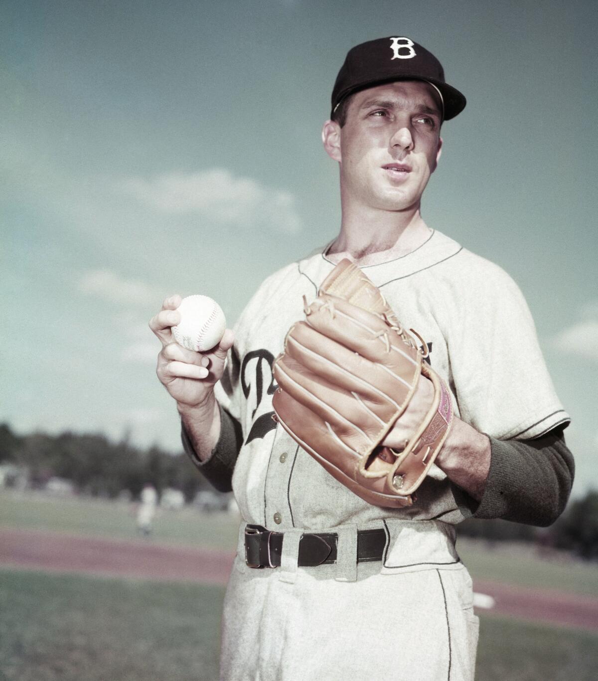 Brooklyn Dodgers pitcher Carl Erskine holds the ball and looks across the field.