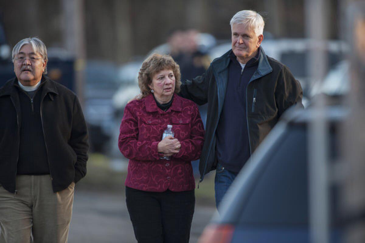 Passersby console each other Friday near the site of the shootings in Newtown, Conn., that left 28 dead, including 20 schoolchildren.