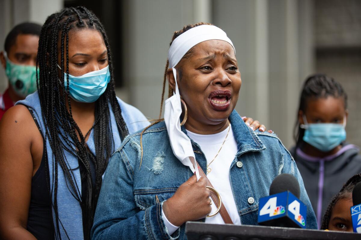 A woman cries while speaking at a news conference 