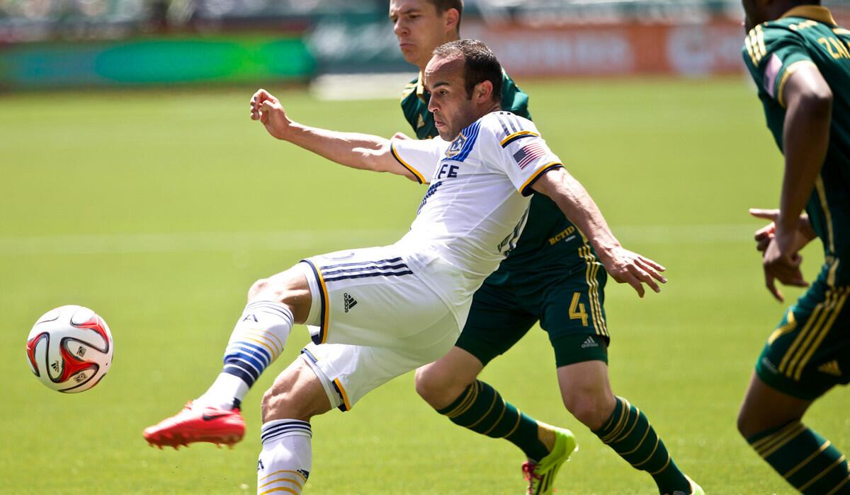 Galaxy midfielder Landon Donovan volleys a pass against Timbers midfielder Will Johnson during their MLS game on Sunday in Portland.