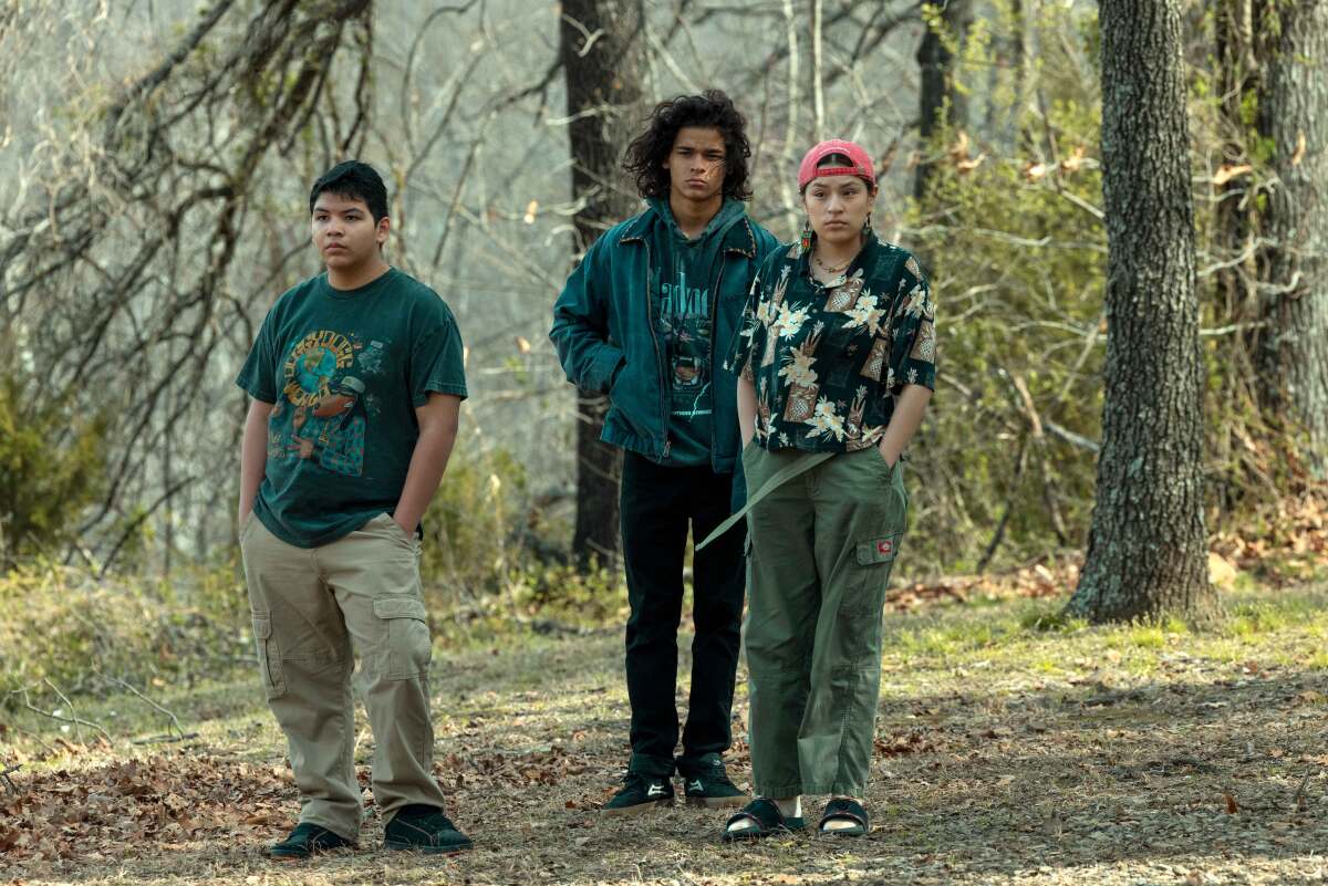 Three teenagers standing in a grove of trees