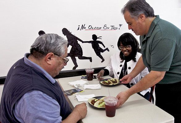 Co-owner Armando De La Torre serves a taco lunch to David Hernandez and Joanne Moore.