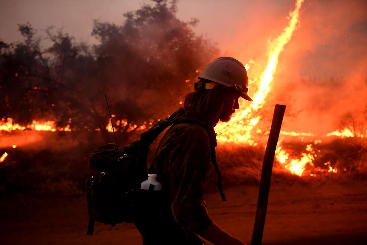 A firefighter helps to set back fires as the El Dorado fire approaches in Yucaipa on Monday.