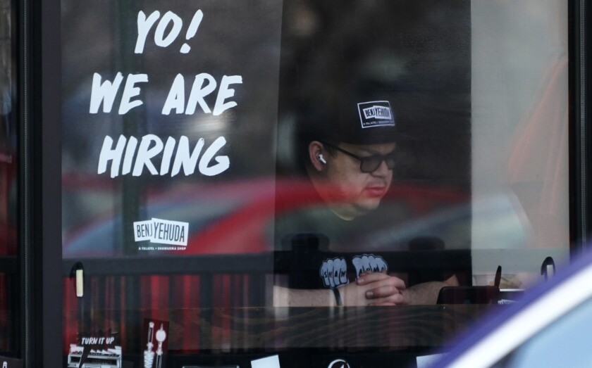 A help-wanted sign in a business window says "Yo! We are hiring"
