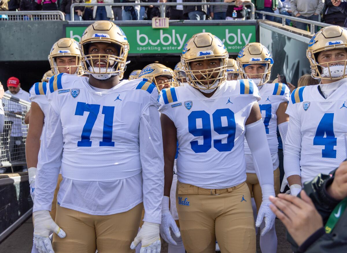 UCLA offensive lineman Raiqwon O'Neal and defensive lineman Jacob Sykes lead the team on the field against Oregon.