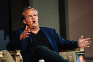 Actor and author Matthew Perry speaks with his hands outstretched onstage at the Los Angeles Times Festival of Books.