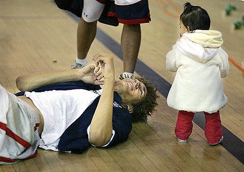 FLOOR SHOW: Robin Lopez plays with a youngster after the game. Of the twins, Robin has the wilder hair and quiter disposition. He'd rather sketch than carry on a conversation.