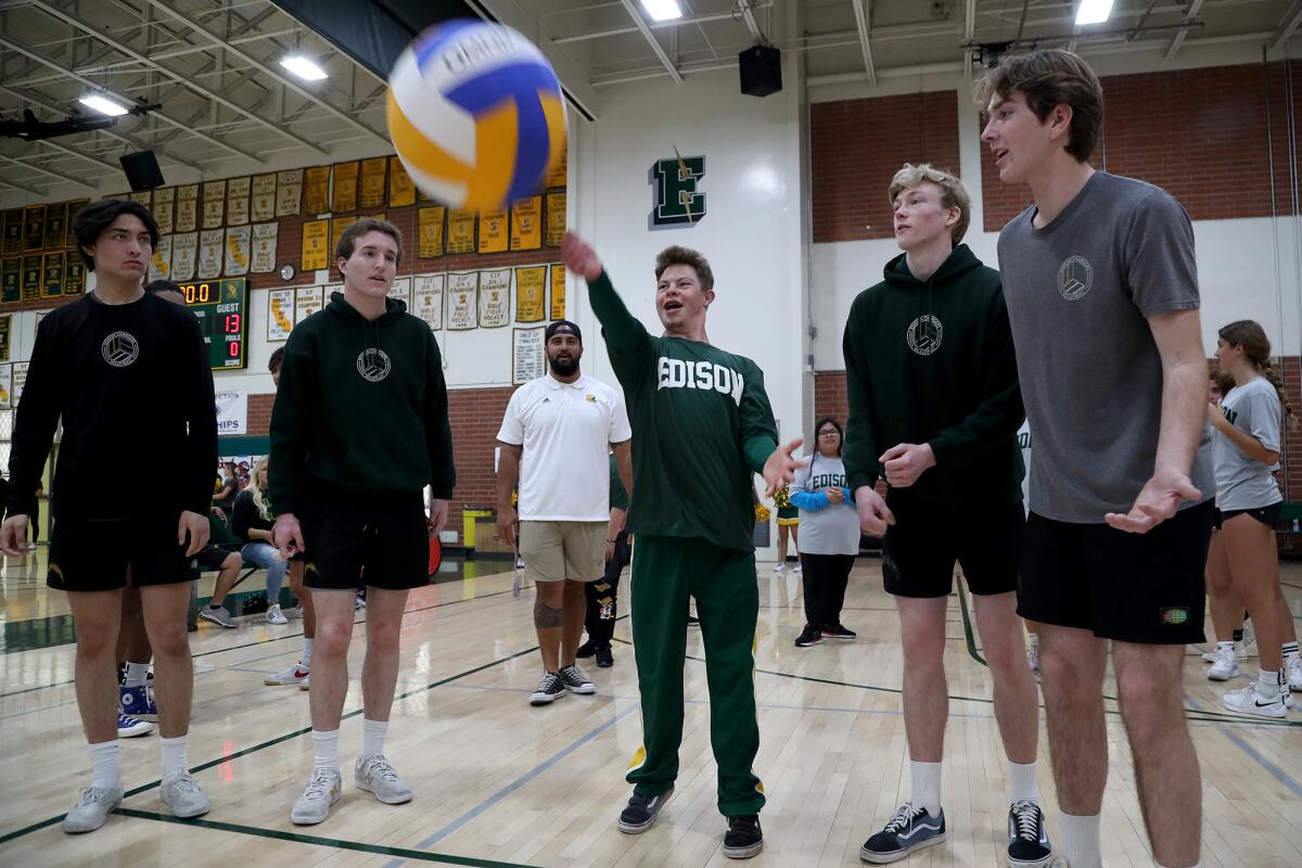 Edison High Special Abilities Cluster student Trevor Henricks, center, is coached how to serve ball by volleyball players. 