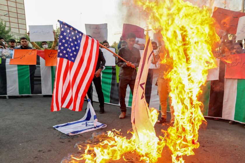 Iranian students from the Islamic Basij volunteer militia burn US and Israeli flags in the capital Tehran, on July 16 2022, during a protest against the US President's visits to Israel and Saudi Arabia. - US ties to Gulf powers in particular have been roiled by multiple issues in recent years, notably Washington's push for a deal to curb Iran's suspect nuclear programme and its tepid response to attacks on Saudi oil facilities in 2019 claimed by Yemen's Iran-backed Huthi rebels. (Photo by ATTA KENARE / AFP) (Photo by ATTA KENARE/AFP via Getty Images)