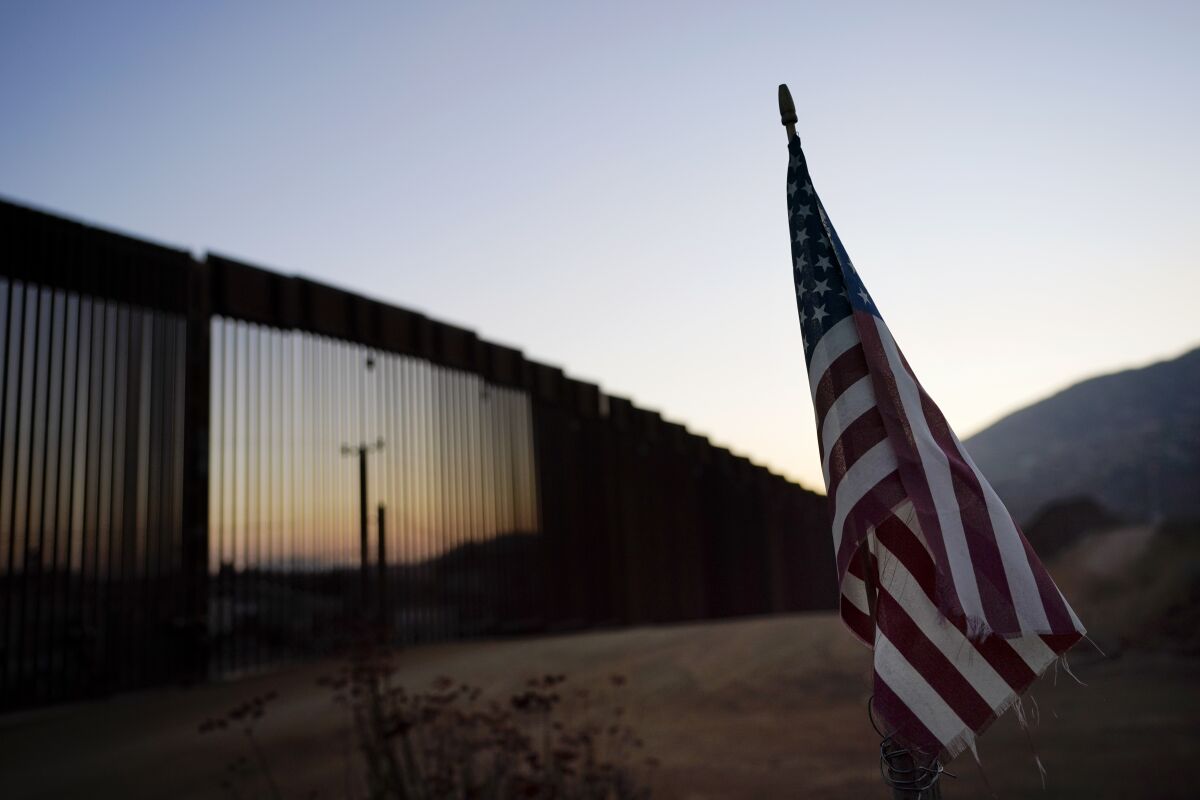 An American flag sits near the border wall in Tecate, Calif. 