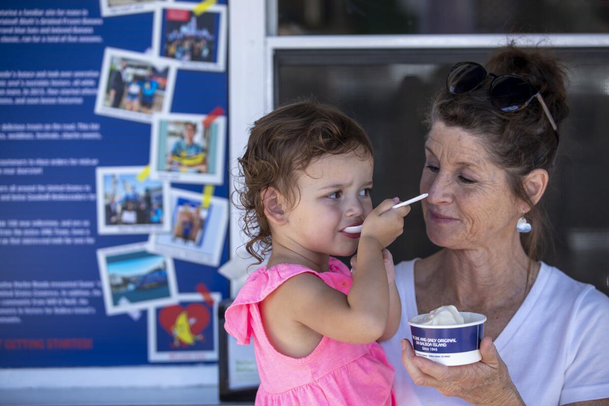 McKenna Contois, 2, eats ice cream as her grandmother Christine Herman watches.