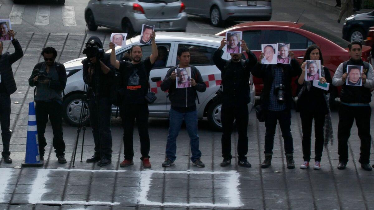 Journalists hold up photos of Javier Valdez and other slain colleagues at the Angel of Independence monument in Mexico City on May 16, 2017, to call attention to the latest wave of killings of journalists.