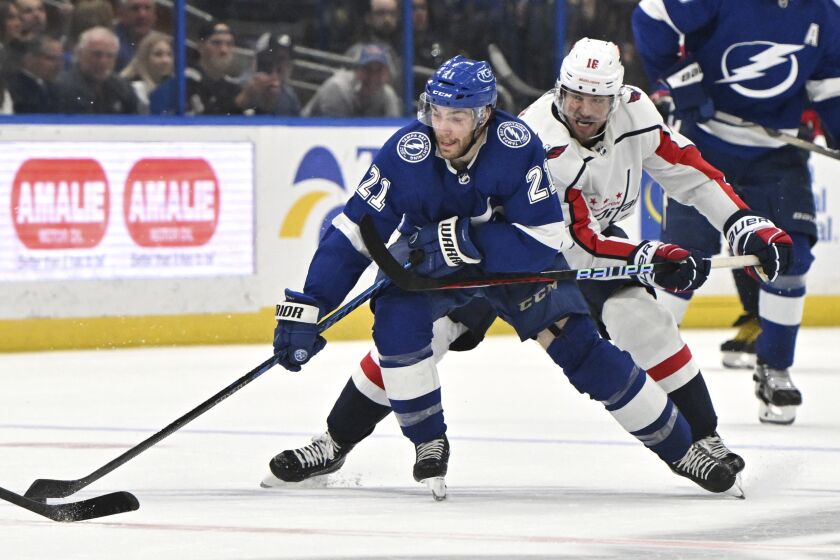 Tampa Bay Lightning center Brayden Point (21) reaches for the puck as Washington Capitals center Craig Smith (16) defends during the second period of an NHL hockey game Thursday, March 30, 2023, in Tampa, Fla. (AP Photo/Jason Behnken)