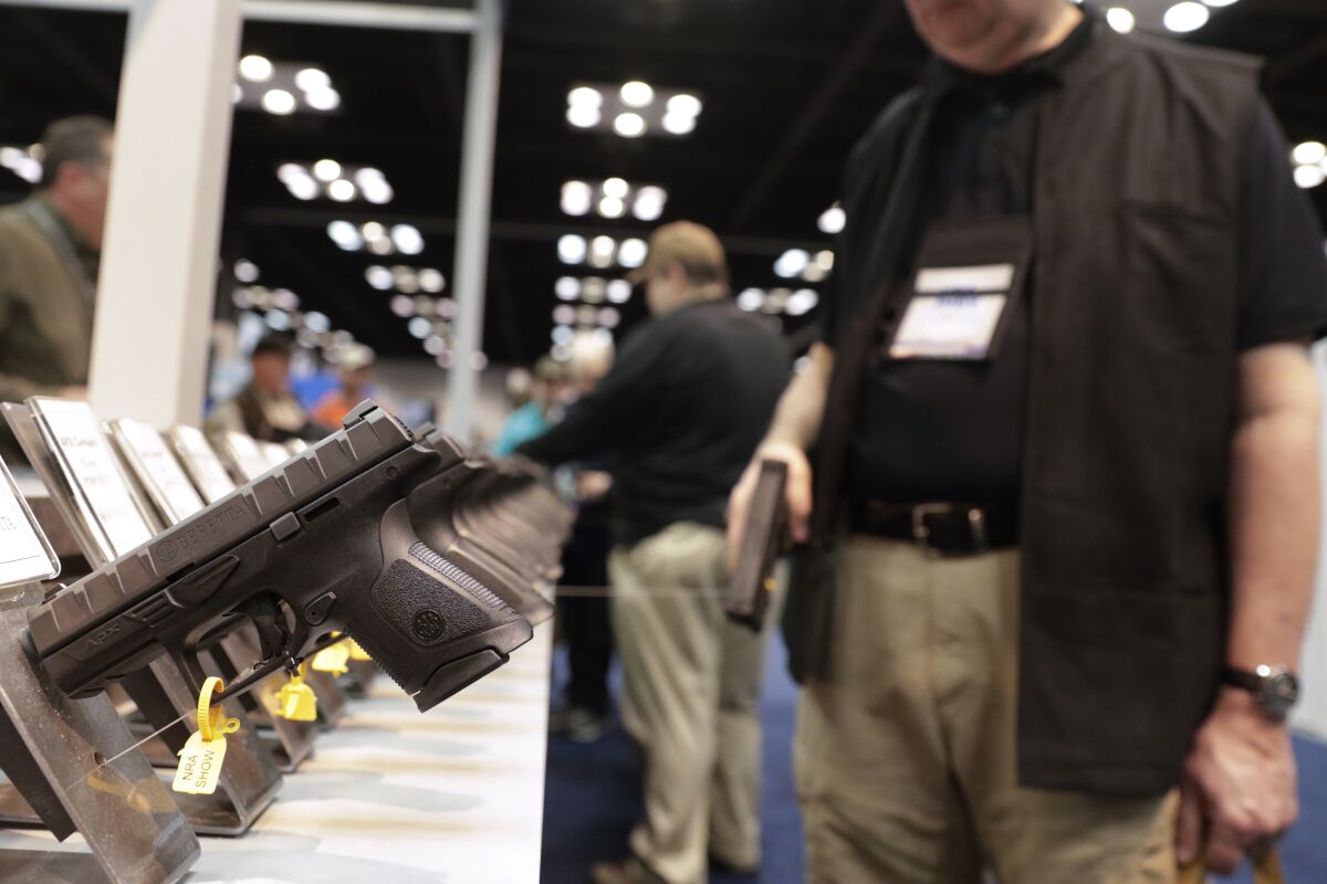 A gun enthusiast looks over the display of pistols in the exhibition hall at the National Rifle Association 