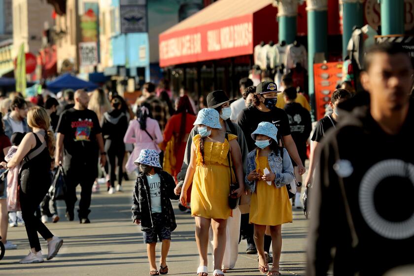 LOS ANGELES, CALIF. - MAR. 21, 2021. A crowd of people descends on Venice Beach, with some wearing masks and others not, on Sunday, Mar. 21, 2021, during the first weekend after coronavirus restrictions were eased in Los Angeles County. (Luis Sinco/Los Angeles Times)
