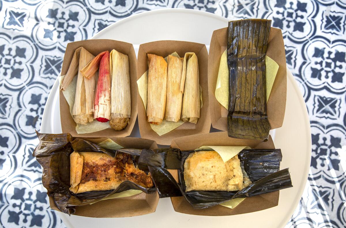 Assorted tamales wrapped in corn husks and banana leaves from Tamales Elena Y Antojitos.