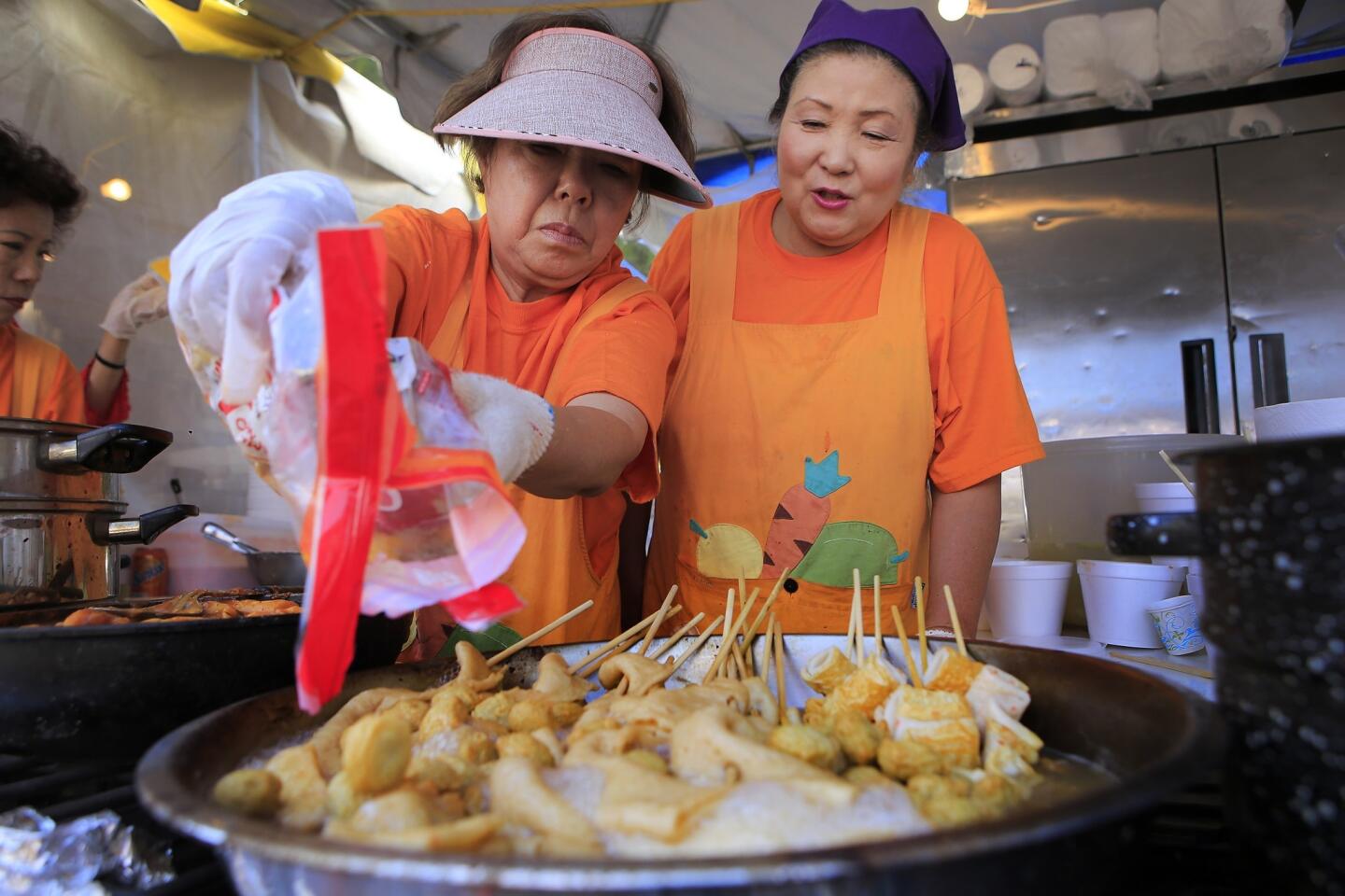 Lily Moon, right, and Kyung Cha prepare fish cakes in a booth at the Los Angeles Korean Festival at Seoul International Park in Los Angeles.