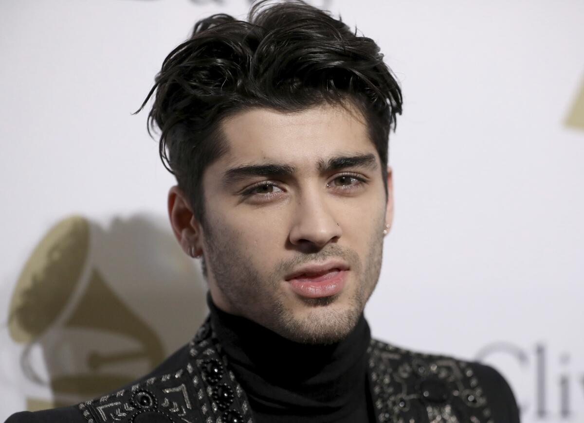 Zayn Malik poses at a premiere in a black turtleneck and bedazzled black jacket