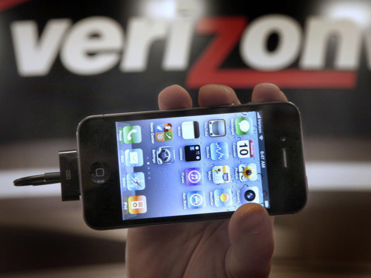 In this Feb. 10, 2011 file photo, Chris Cioban, manager of the Verizon store in Beachwood, Ohio, holds up an Apple iPhone. Verizon reached a deal with Apple to sell far more iPhones than it actually will be able to, according to an investment research firm's analysis.
