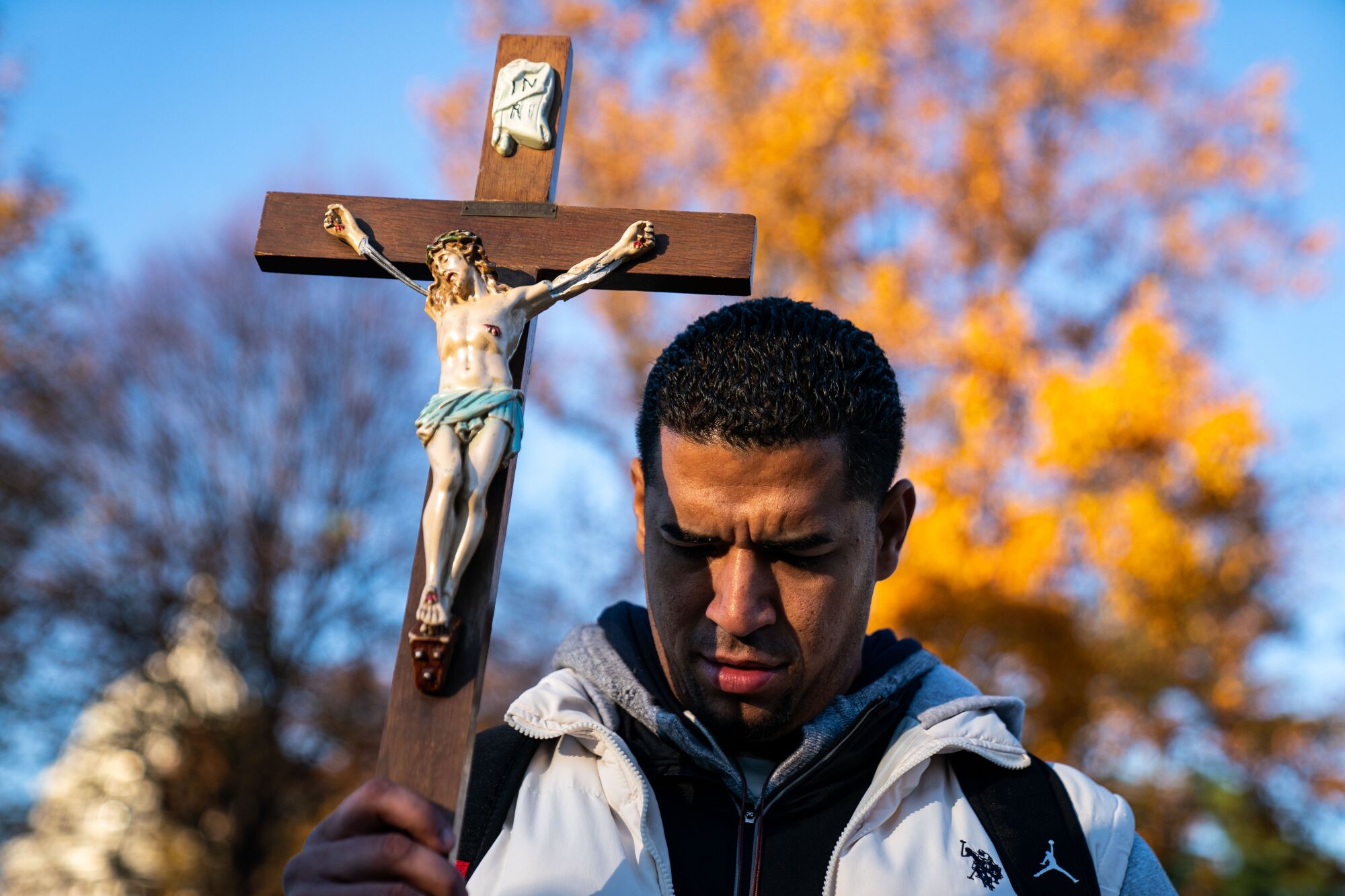 Juanito Estevez bows his head and holds a cross