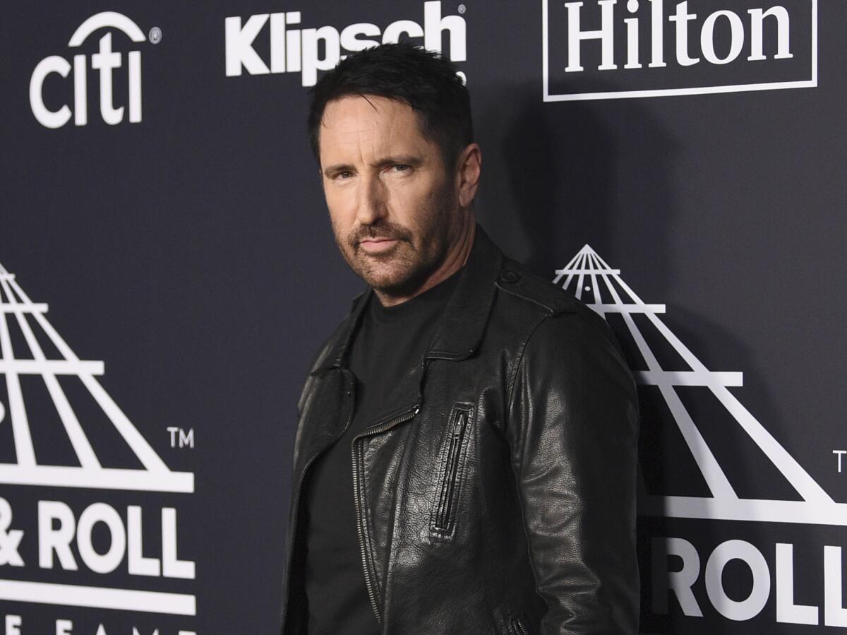 A man with a goatee and a black leather jacket poses at an event