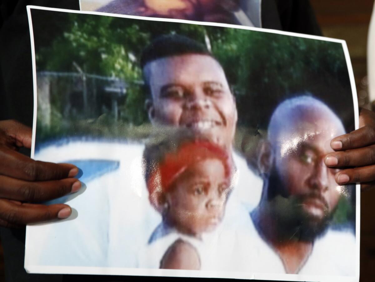 Michael Brown Sr. holds up a photo of himself, at right, his son, Michael Brown, top left, and a young child. (Jeff Roberson / AP)
