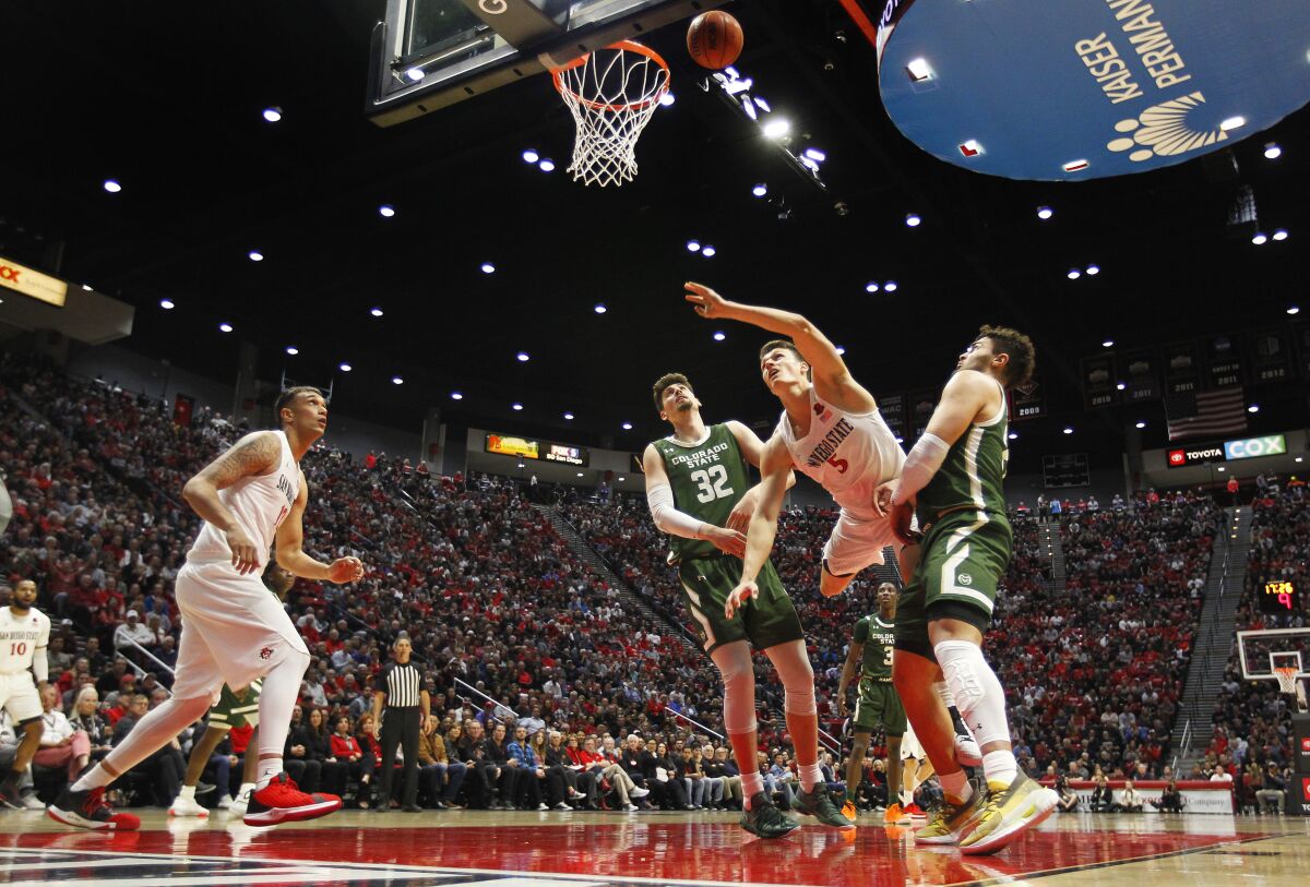 SDSU's Yanni Wetzell is fouled by Colorado State's Nico Carvacho (left) as David Roddy defends.