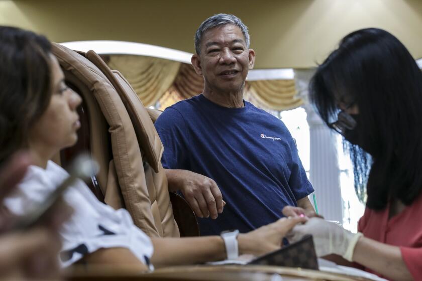 Brea, CA - September 11: Vietnamese American Phuoc Dam, center, who has owned salon business for more than 20-years, was badly effected during pandemic restrictions. Dam stands in his business Queen Nail and Spa on Saturday, Sept. 11, 2021 in Brea, CA. (Irfan Khan / Los Angeles Times)