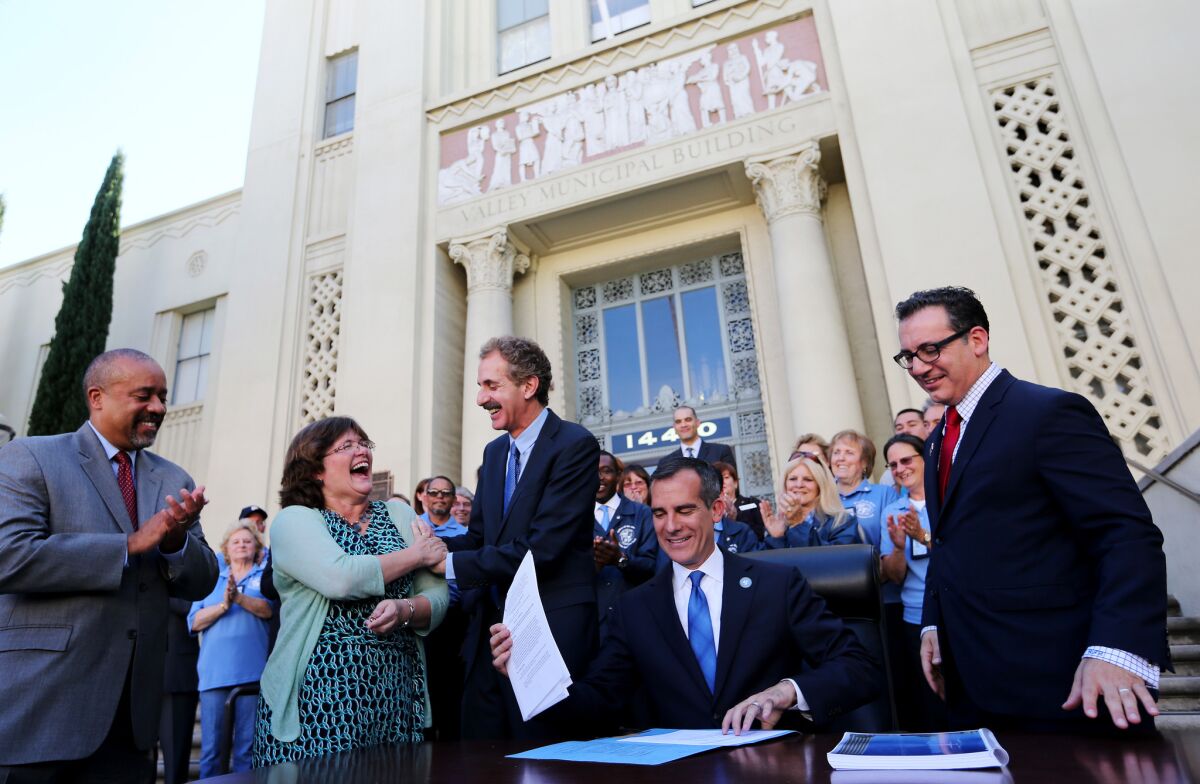 Lucy Jones, U.S. Geological Survey seismologist, second from left, celebrates with City Atty. Mike Feuer, center, as Mayor Eric Garcetti signs sweeping legislation to require earthquake retrofits on 15,000 buildings in Los Angeles on Friday.