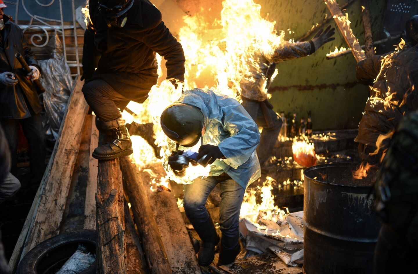 Protesters catch fire as they stand behind burning barricades during clashes with police in Kiev, Ukraine.