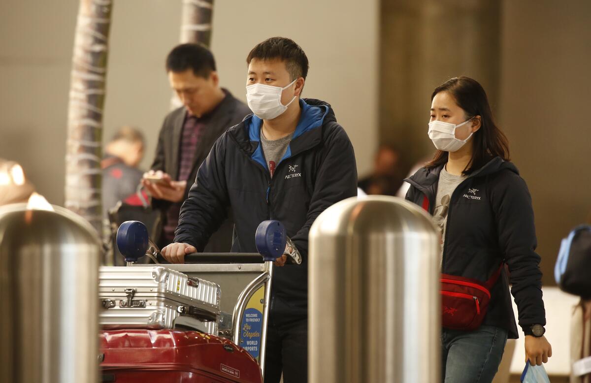 Travelers wear masks at the Tom Bradley International Terminal at Los Angeles International Airport in January.