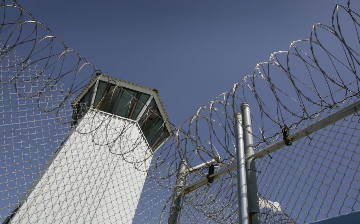 A guard tower at Richard J. Donovan Correctional Facility seen through a chain link fence and barbed wire.