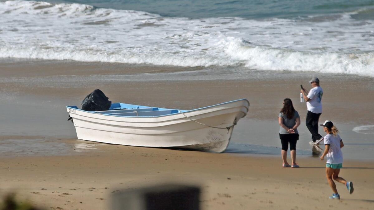 Beachgoers photograph a panga-style boat that went ashore at Crystal Cove State Park on Tuesday.