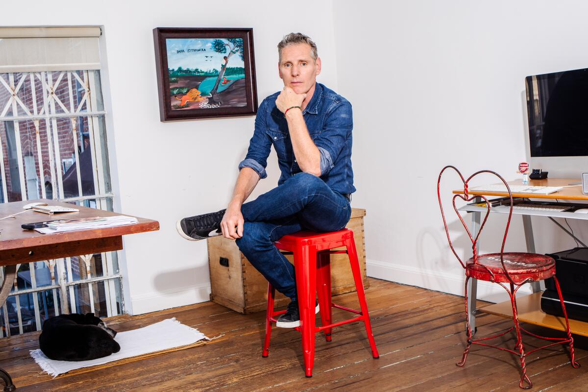 A man sits on a red stool.