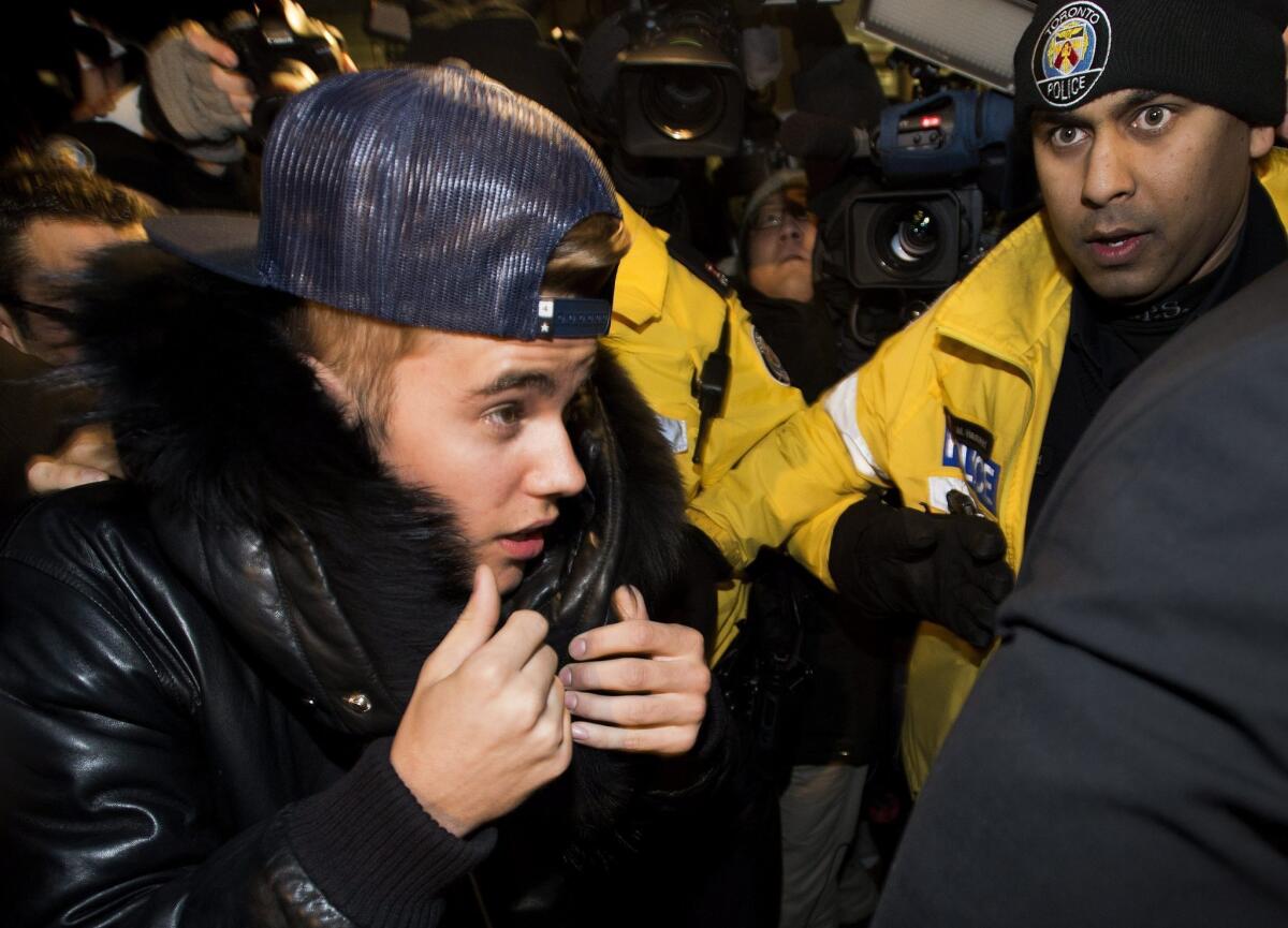 Canadian musician Justin Bieber is swarmed by media and police officers as he turns himself in Wednesday to Toronto police for an expected assault charge.
