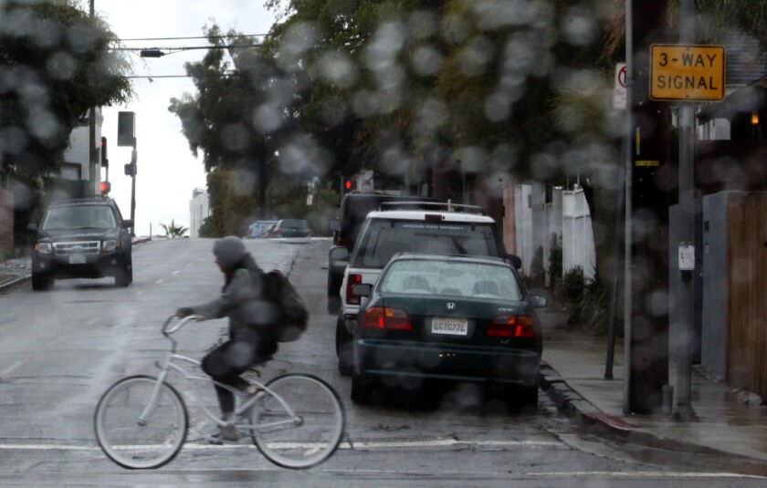 A bicyclist makes her way along Main Street during a morning rain in Venice.