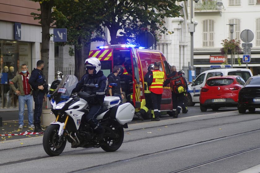 French policemen and firemen stand next to Notre Dame church after a knife attack, in Nice, France, Thursday, Oct. 29, 2020. French anti-terrorism prosecutors are investigating a knife attack at a church in the Mediterranean city of Nice that killed two people and injured several others. (AP Photo/Alexis Gilli)