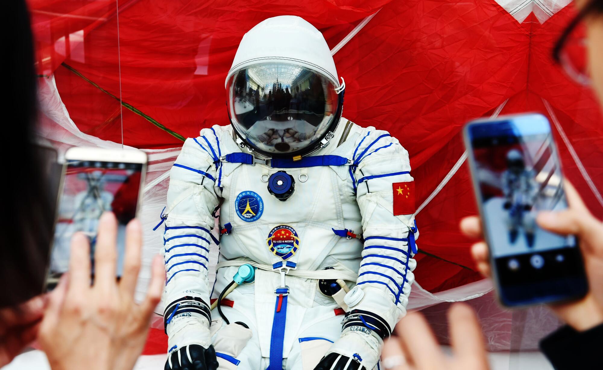 Visitors take photos of a space suit during an event marking China's Space Day