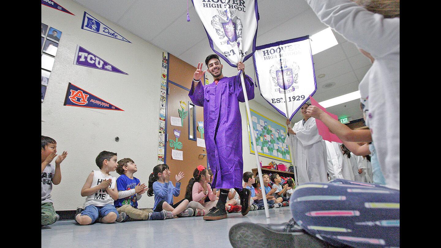 Hoover High School senior Ara Sukiasyan waves to Mark Keppel Elementary School kindergarten students who lined the hall to greet them on Friday, May 27, 2016. Inspired by social media, seniors from Hoover visited Keppel and Toll to inspire the younger students with the power of graduation gowns being worn by students from the 2016 graduating class.