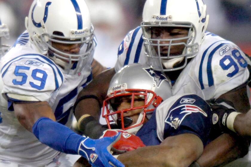 Colts defensive end Robert Mathis (98) helps bring down Patriots running back Corey Dillon.