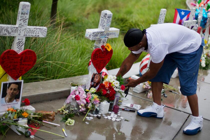 David Collins leaves flowers at a cross honoring Shane Evan Tomlinson. A retired carpenter from Illinois built and delivered crosses for each of the 49 victims of the Pulse nightclub massacre in Orlando, Fla.